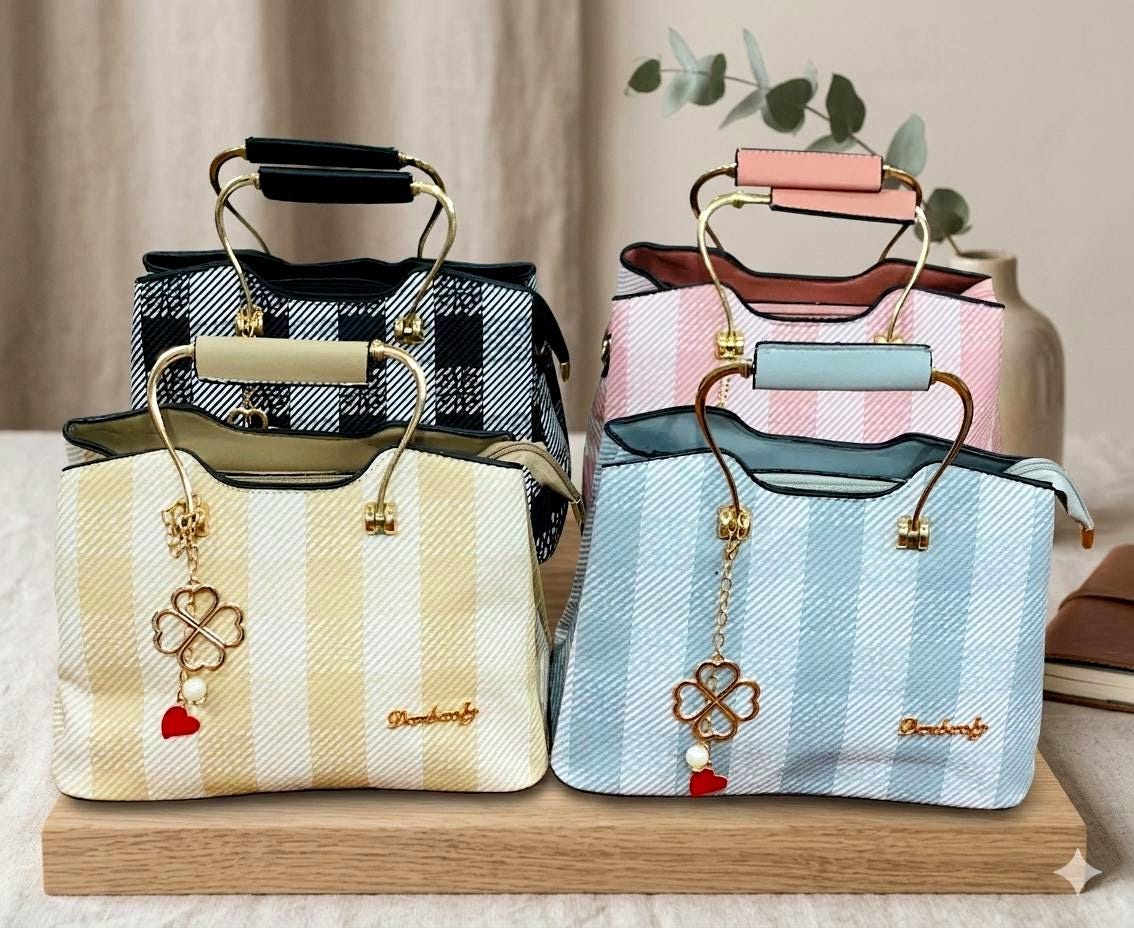 Lace & Luxe striped satchel handbag with gold top handle, leather shoulder strap, and decorative clover charm on textured leather.